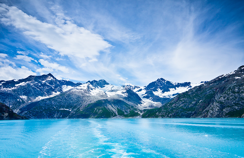 a body of water with mountains and blue sky in Glacier Bay National Park, Alaska